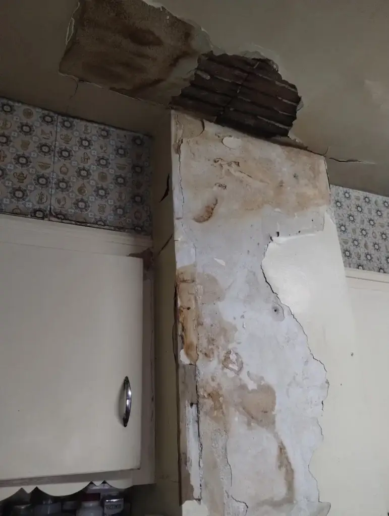 Damaged plaster wall exposing wood lath