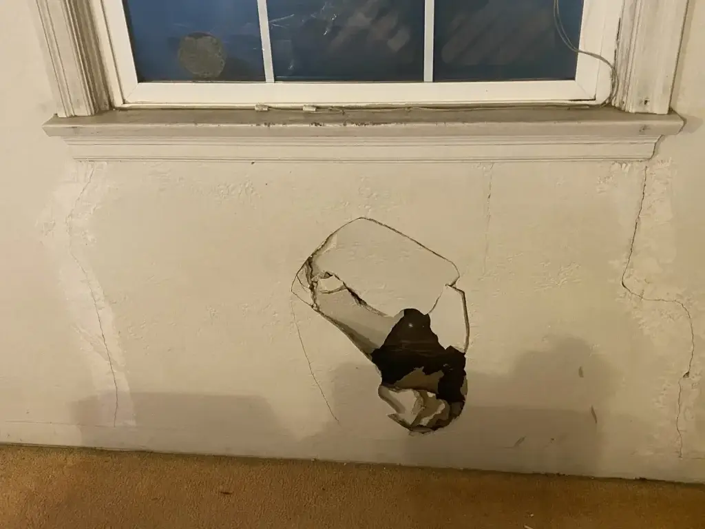 Impact hole in drywall below window